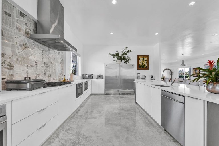 Bright galley kitchen with white cabinetry and stone finishes
