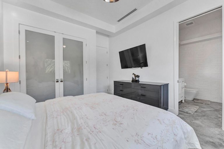 Guest bedroom with television, mirrored closet, and neutral finishes