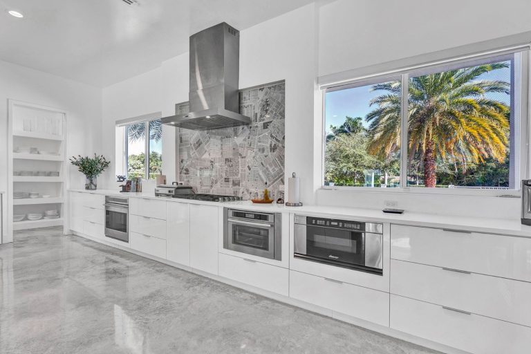 White kitchen cabinetry with stone backsplash and built-in cooktop