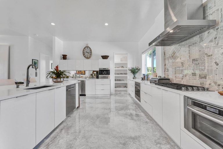 Long modern kitchen corridor with white cabinetry and stone backsplash