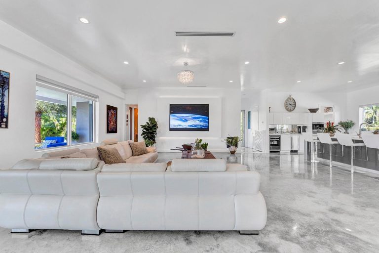 Open living room with media wall and adjoining kitchen
