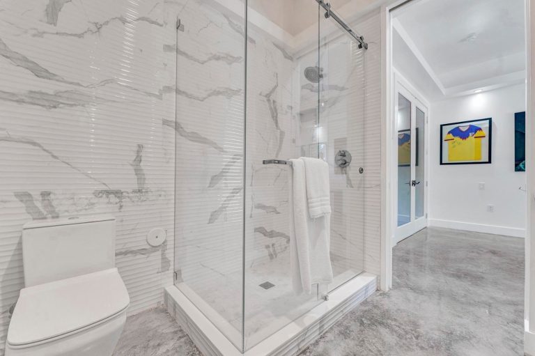 Walk-in glass shower with marble-patterned walls and built-in bench