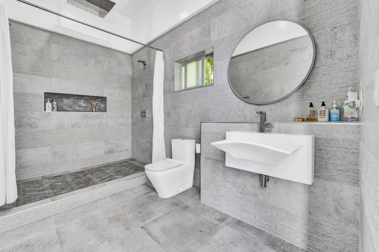 Modern bathroom with walk-in shower, floating vanity, and round mirror